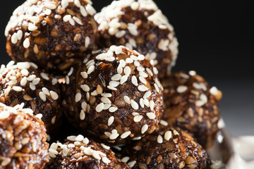 Raw homemade paleo energy balls with rolled oats, nuts, dates and sesame, horizontal, close up. Vegan sweet dessert