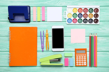 School supplies with smartphone on mint wooden table
