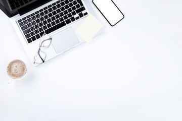 Laptop computer with smartphone, glasses and cup of coffee on white background