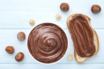 Bread with melted chocolate and hazelnuts on wooden table