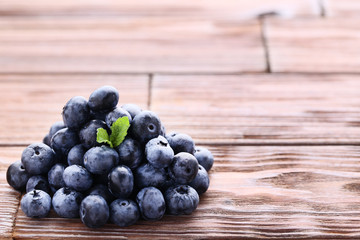 Ripe blueberries with green leafs on wooden table