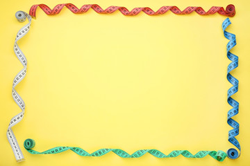 Colorful measuring tape on yellow background