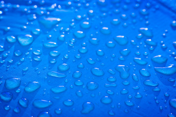 Large drops of water on a blue textile with a waterproof effect. Water-repellent impregnation. Texture drops on the fabric.