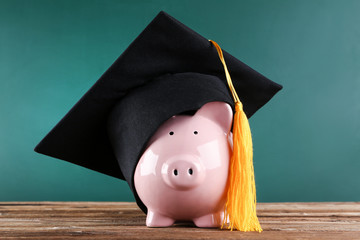 Piggybank with graduation cap on brown wooden table