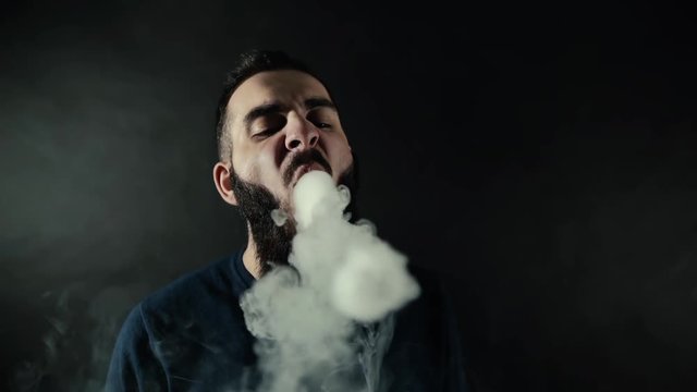 smok einweg vape Smoking vape. vaping man holding a mod. Vape Rings. A man launches a ring  of smoke. Tricks with smoke Stock Photo main image 1