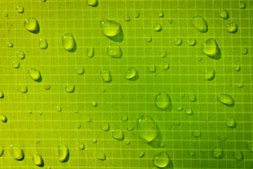 Large drops of water on green textiles with a waterproof effect. Water-repellent impregnation. Texture drops on the fabric.