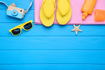 Fashion clothing with starfish and sunscreen on blue wooden table