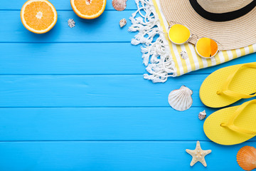 Fashion clothing with seashells and orange fruit on blue wooden table