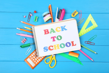 Text Back To School on notepad with stationery on blue wooden table