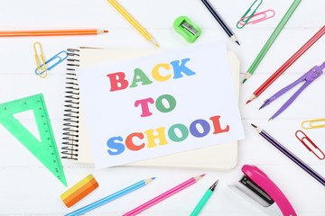 Text Back To School with stationery on white wooden table