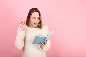 Young girl with book on pink background