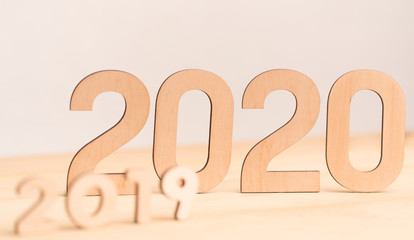 Wooden numbers from 2019 to big 2020 on light background