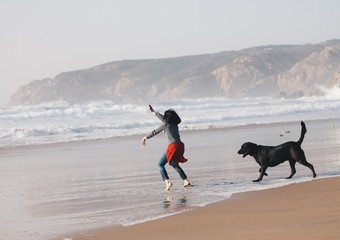 little girl playing and jumping with dog at guincho beach in Portuga