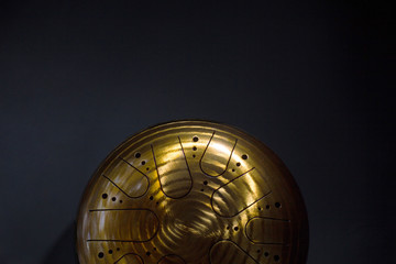 Golden hang drum half on a black background, top view, copy space