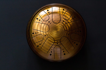 Golden hang drum on a black background, near view, centered object