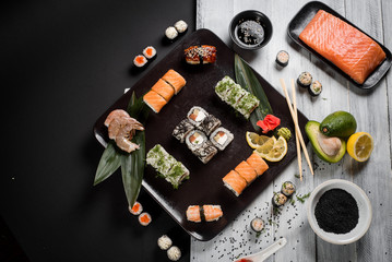 Obraz na płótnie Canvas Sushi set with salmon, eel, tuna, avocado, cream cheese Philadelphia, caviar, chuka. Sushi menu. Japanese food on black and white background