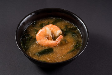 Hot miso soup with shrimp in bowl on black background. Japanese food