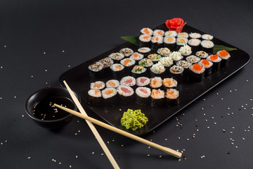 Japanese sushi rolls set served on black plate on dark background