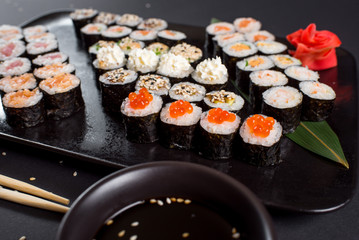 Japanese sushi rolls set served on black plate on dark background