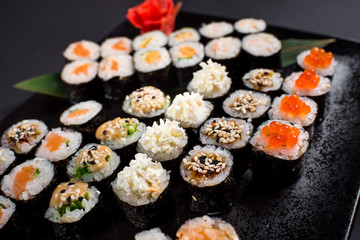 Japanese sushi rolls set served on black plate on dark background