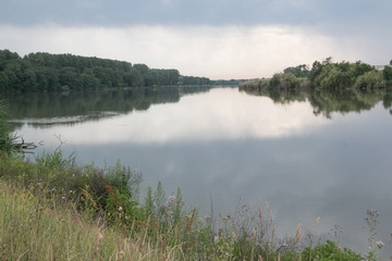 Blue sky and green forest reflected in the Kuban river