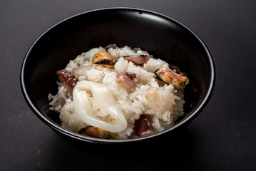 Dish of rice with seafood on black