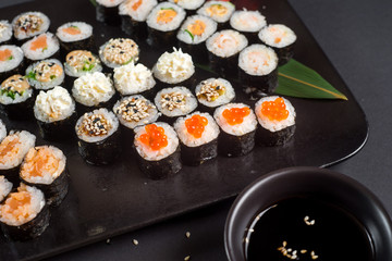 Japanese sushi rolls set served on black plate on dark background