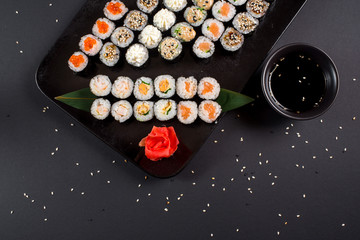 Obraz na płótnie Canvas Japanese sushi rolls set served on black plate on dark background
