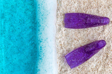 Minimal beach creative concept summer vacation with blue ocean and snorkel fins on sandy beach.