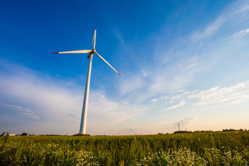 Single wind turbine producing electricity for agricultural area. Summer landscape