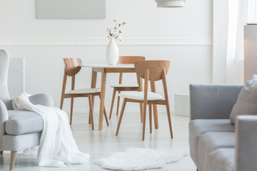 Grey armchair and sofa in trendy living room with white wall