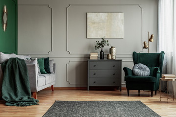 Abstract painting on grey wall o contemporary living room interior with emerald green armchair with...