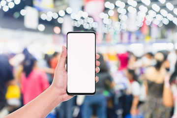 Mobile phone mockup image, hand holding blank screen mobile smart phone with blurred  Crowd of people in the shopping store, mobile apps, shopping online, internet banking concept.