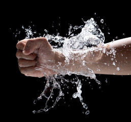 Fist punch into water with big splashes flying in the air isolated on black background