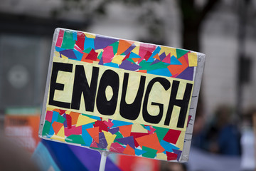 A protestor holds a political banner with enough message