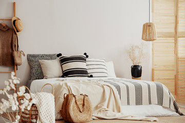 Stripped bedding on white king size bed, copy space on empty wall