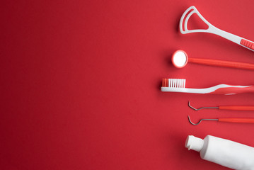 Set of different tools with toothbrushes and toothpaste tube against red background,dental care