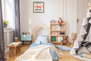 Fotobehang Boho Cozy kids bedroom with blue bedding and warm blanket on the bed, real photo with mockup poster on the floor  © Photographee.eu