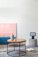 Vase and candle on round coffee table next to open book on the floor