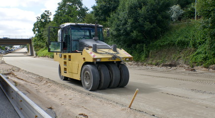 Road renewal, work on the closed highway lane. Preparation work for asphalting with a heavy vibratory roller compactor