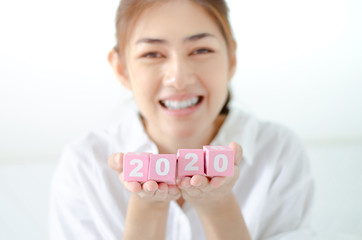 Small pink square wooden box with numbers in Asian women hands.Do not focus on the main object of this image.