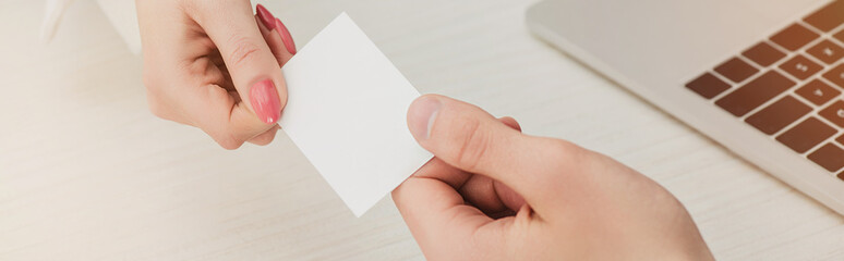 Obraz premium cropped view of businessman and businesswoman holding white empty business card, panoramic shot