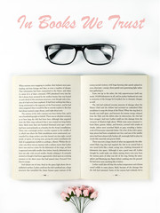 Open book, glasses and flowers on a white background