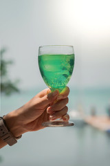 Green water in cocktail glass in woman hand