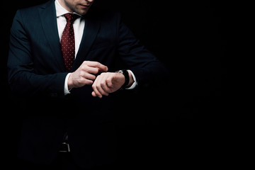 partial view of businessman checking time on watch isolated on black