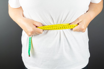 Woman holds a measuring tape around her waist