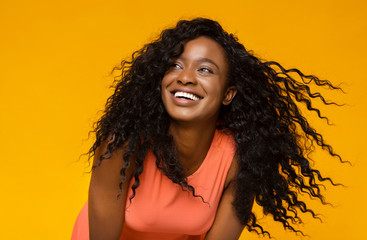 Young african woman laughing on yellow background