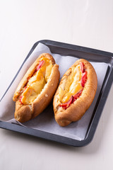 Two hot dog fast food junk fresh sausage cheese sauce isolated on baking tray white background