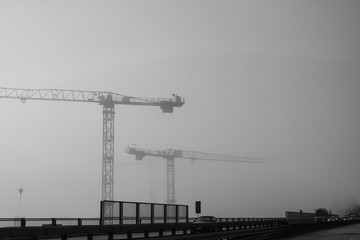 Black and white picture of the road and cranes in mist
