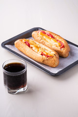 Single glass of cola drink with two hot dog fast food junk fresh sausage cheese sauce isolated on baking tray white background